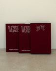 Three red books titled 'Words of Lovers' arranged in a row against a textured off-white wall and concrete floor.